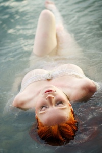 A redheaded woman reclines in the water, from pinterest.com